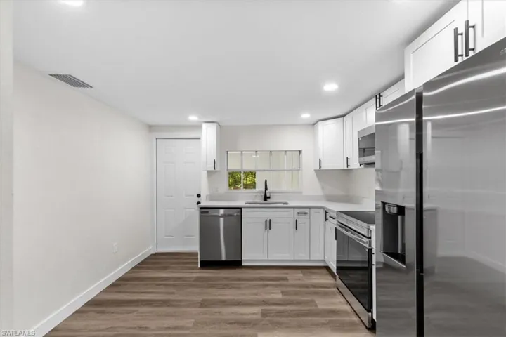 Kitchen featuring white cabinetry, appliances with stainless steel finishes, and wood-type flooring