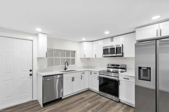 Kitchen featuring sink, hardwood / wood-style flooring, white cabinetry, and stainless steel appliances