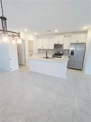 Kitchen featuring refrigerator, stove, light countertops, tasteful backsplash, and recessed lighting
