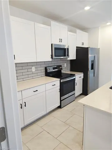Kitchen with stainless steel electric range oven, white cabinets, tasteful backsplash, and recessed lighting