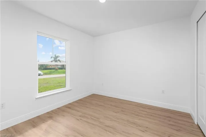 Unfurnished room with a wealth of natural light, light wood-style flooring, and baseboards