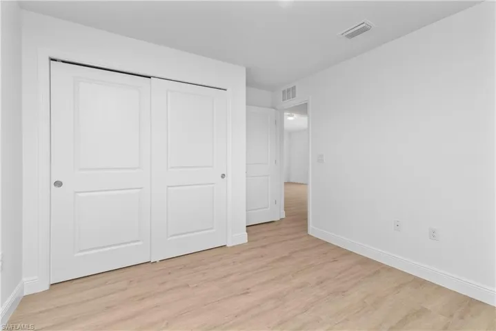 Unfurnished bedroom featuring light wood-style flooring, a closet, visible vents, and baseboards