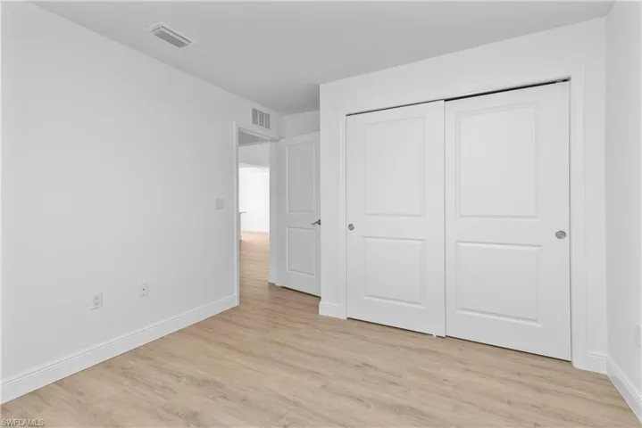 Unfurnished bedroom featuring light wood-type flooring, baseboards, visible vents, and a closet