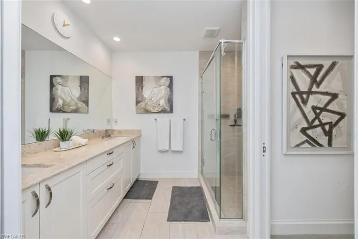 Full bath featuring double vanity, a stall shower, recessed lighting, and light tile patterned floors