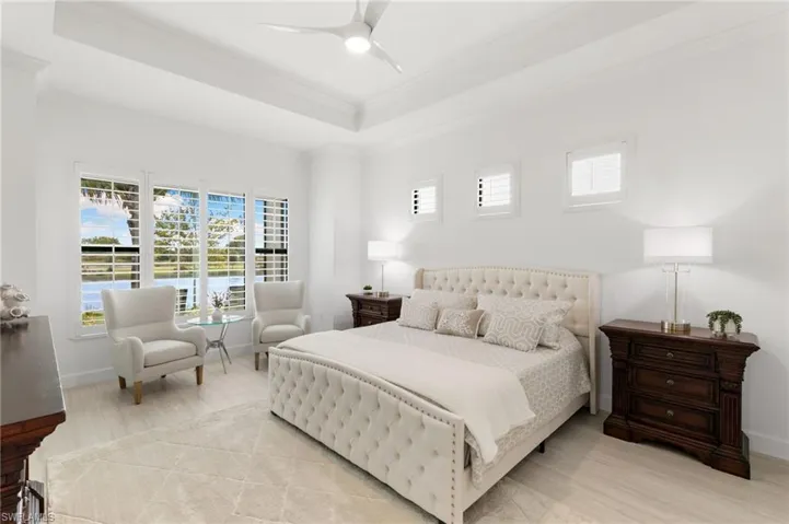 Bedroom with multiple windows, a raised ceiling, wood finished floors, ornamental molding, and ceiling fan
