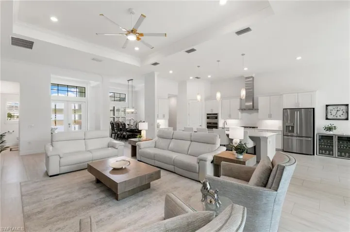Living room featuring a raised ceiling, a ceiling fan, recessed lighting, ornamental molding, and a towering ceiling