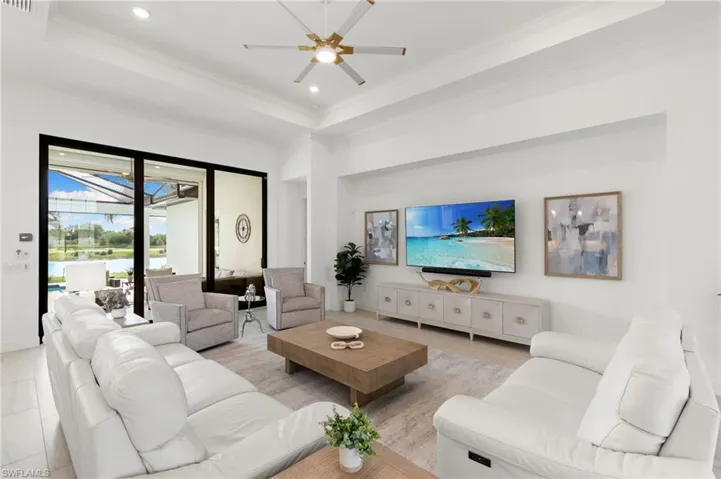 Living area featuring a tray ceiling, recessed lighting, a ceiling fan, crown molding, and a sunroom