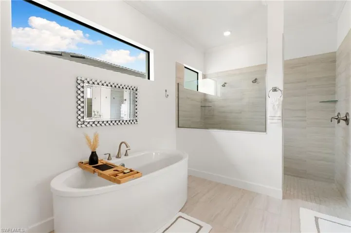 Bathroom featuring walk in shower, ornamental molding, and a soaking tub