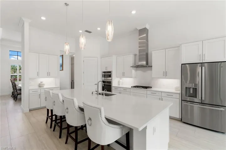 Kitchen featuring stainless steel appliances, ornamental molding, a kitchen breakfast bar, white cabinetry, and an island with sink