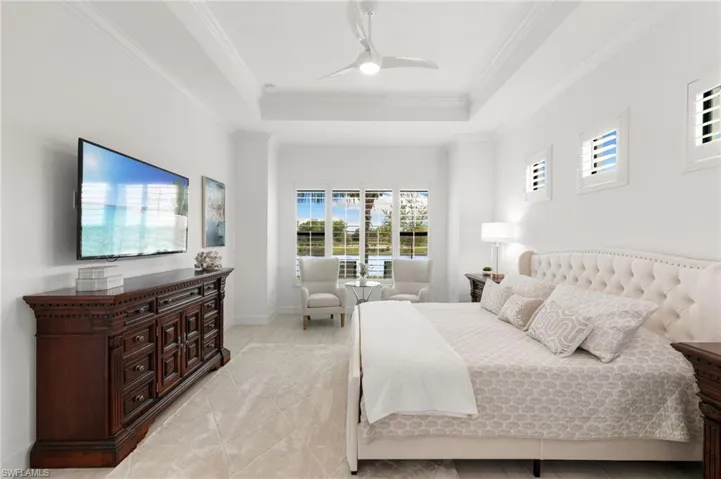 Bedroom with crown molding, a tray ceiling, and a ceiling fan