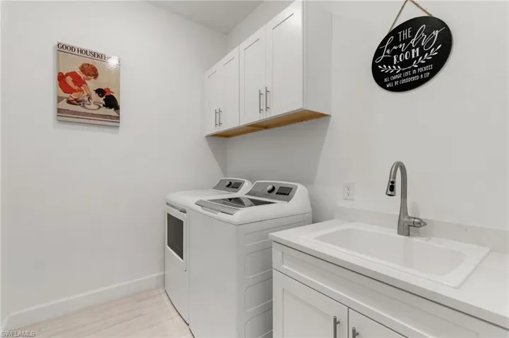 Washroom with washing machine and dryer, light wood-type flooring, and cabinet space
