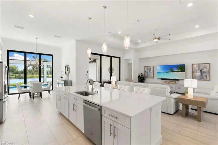 Kitchen featuring ceiling fan, white cabinetry, hanging light fixtures, appliances with stainless steel finishes, and an island with sink