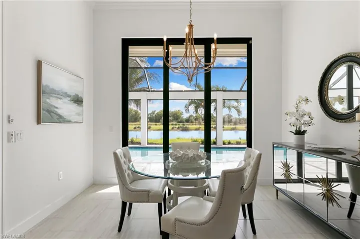 Dining area with healthy amount of natural light, a water view, wood finish floors, ornamental molding, and a chandelier