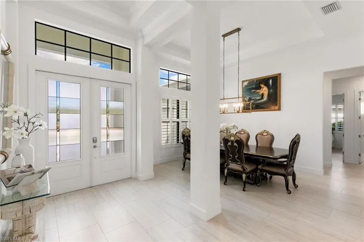 Entrance foyer featuring french doors, healthy amount of natural light, crown molding, a chandelier, and a high ceiling