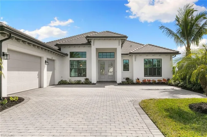 View of front of property with decorative driveway, french doors, a garage, and stucco siding