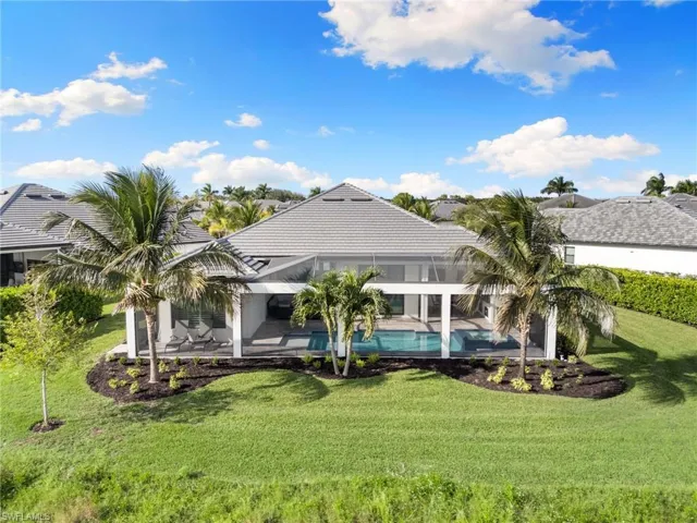 Back of property featuring an outdoor pool, a patio, and a lawn