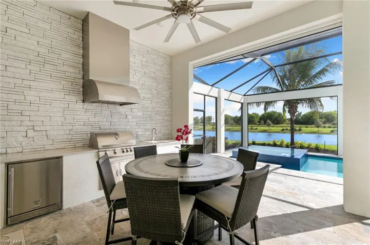 Dining area with a sunroom, ceiling fan, a water view, and stone tile flooring