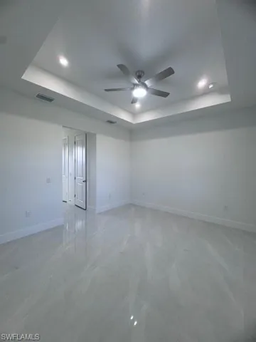Spare room with baseboards, visible vents, a ceiling fan, and a raised ceiling