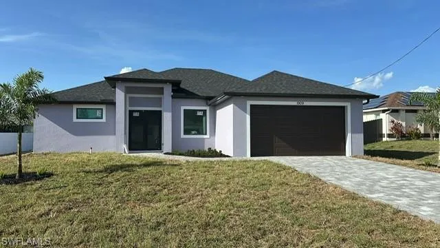 View of front facade featuring stucco siding, an attached garage, a front yard, and decorative driveway