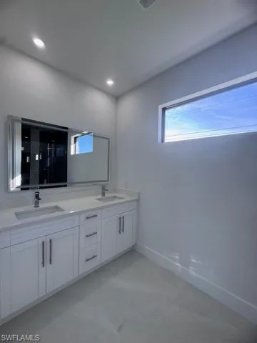 Full bath featuring double vanity, a shower, baseboards, and a sink