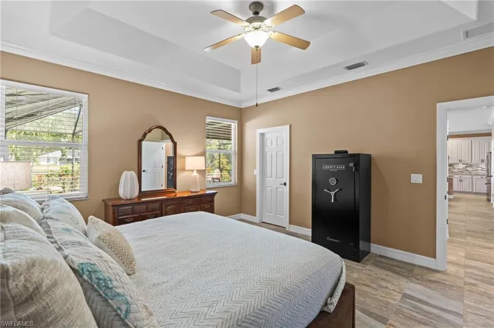 Bedroom featuring a raised ceiling, ornamental molding, a ceiling fan, and baseboards