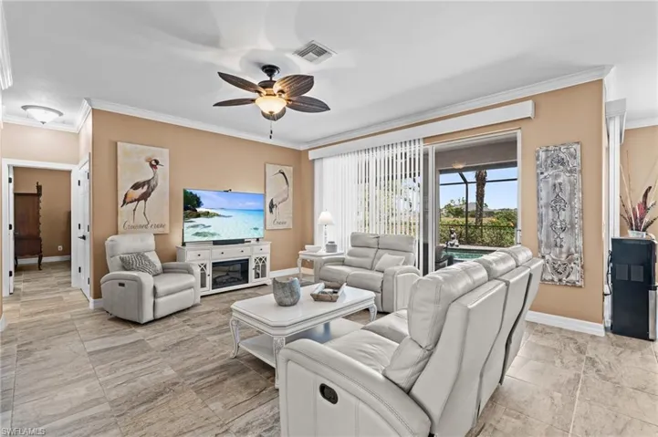 Living area featuring ceiling fan, baseboards, and crown molding