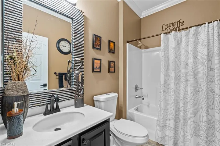 Bathroom with ornamental molding, vanity, toilet, and shower / tub combo