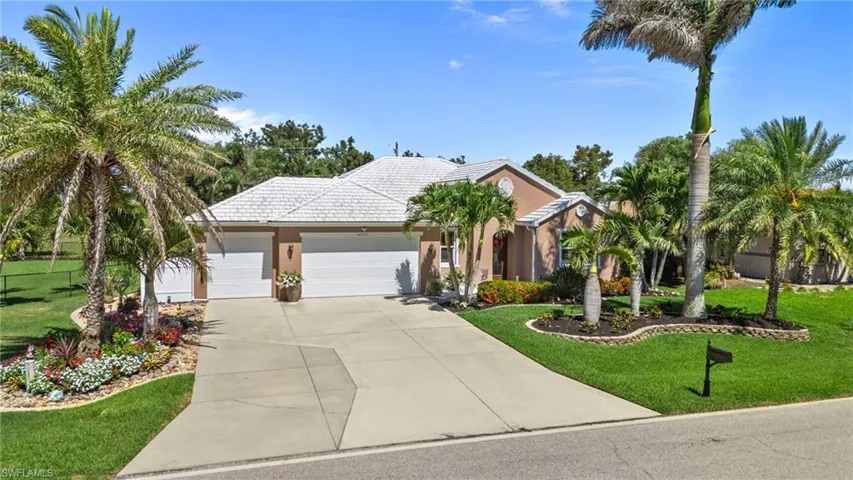 View of front of home with a front lawn, a garage, a tile roof, and concrete driveway