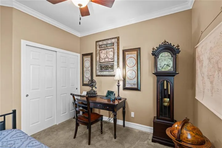 Home office featuring carpet flooring, a ceiling fan, ornamental molding, and baseboards