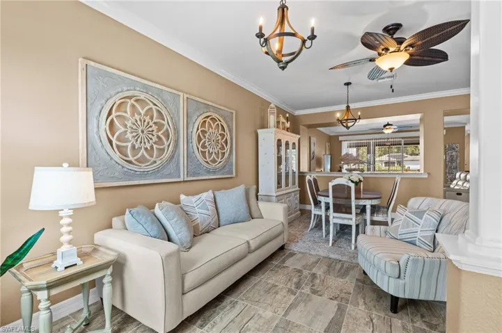 Living area featuring a chandelier, crown molding, and a ceiling fan