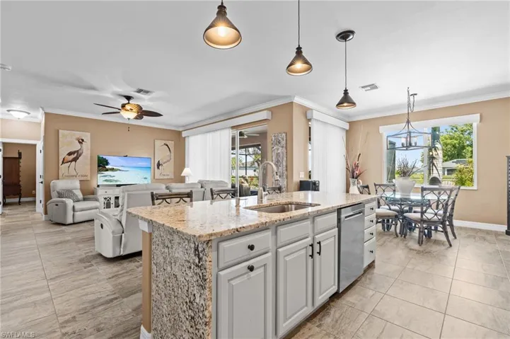 Kitchen with a sink, dishwasher, a center island with sink, a ceiling fan, and ornamental molding