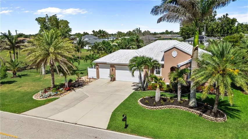 View of front of property with a garage, driveway, a front yard, stucco siding, and a tiled roof