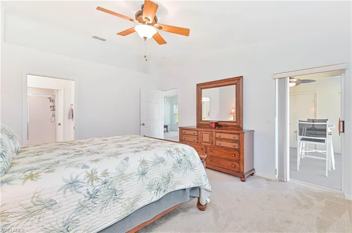 Bedroom with a ceiling fan, light carpet, and ensuite bathroom