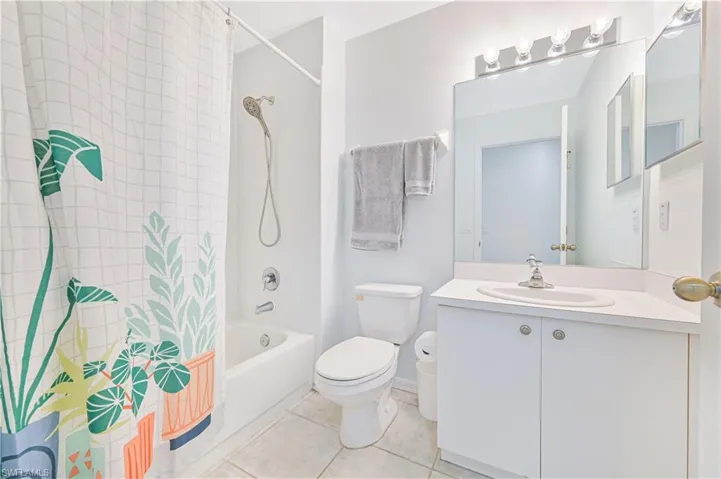 Bathroom with shower / bath combo with shower curtain, vanity, and light tile patterned floors