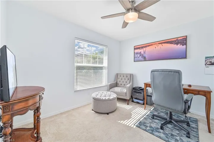 Carpeted home office featuring baseboards and a ceiling fan