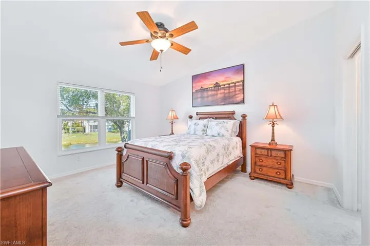 Bedroom with light carpet, ceiling fan, and lofted ceiling