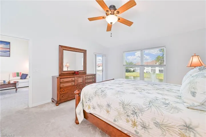 Carpeted bedroom featuring a ceiling fan and vaulted ceiling