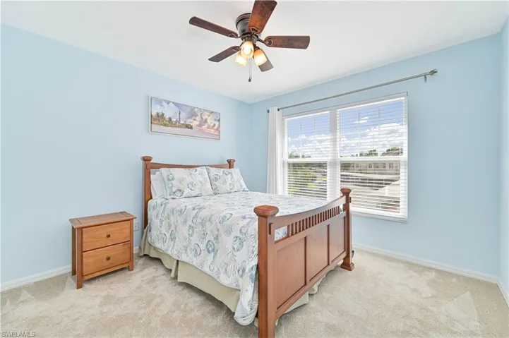 Carpeted bedroom with baseboards and a ceiling fan