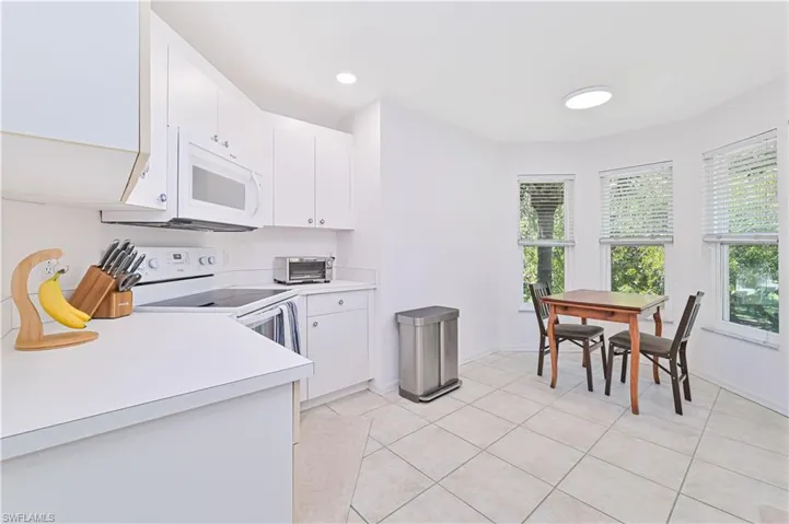 Kitchen with light countertops, white appliances, white cabinets, light tile patterned floors, and recessed lighting