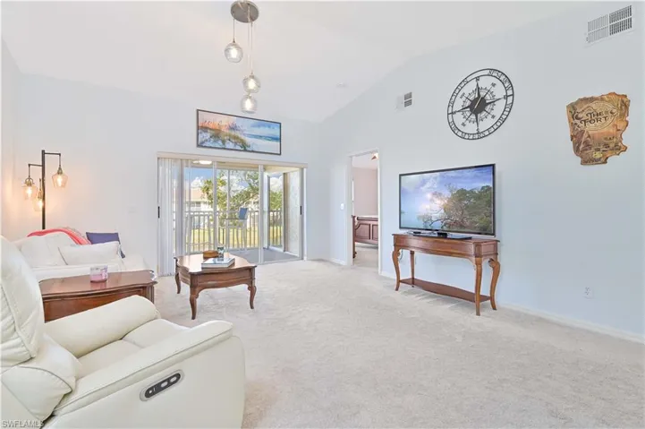 Living area with carpet floors and high vaulted ceiling