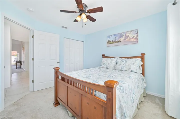 Bedroom featuring a ceiling fan, light carpet, and a closet