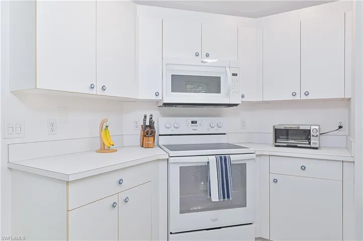 Kitchen with white appliances, light countertops, and white cabinets