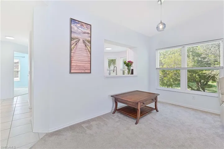 Empty room with light colored carpet, lofted ceiling, and light tile patterned flooring