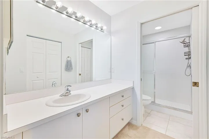 Full bathroom featuring vanity, a shower stall, light tile patterned floors, and a closet