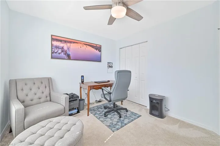 Carpeted home office featuring baseboards and a ceiling fan