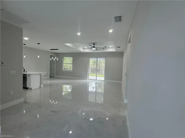 Spare room with ceiling fan, a raised ceiling, and light tile flooring
