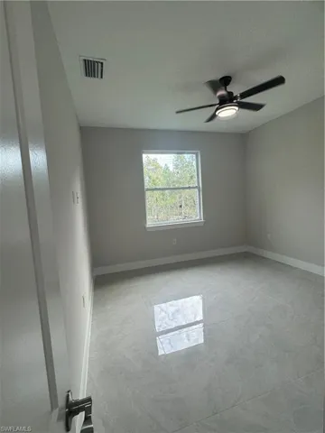 Tiled spare room featuring ceiling fan