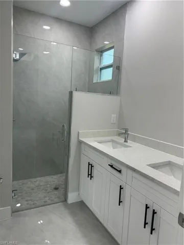 Bathroom featuring tile floors, a shower with door, and dual vanity