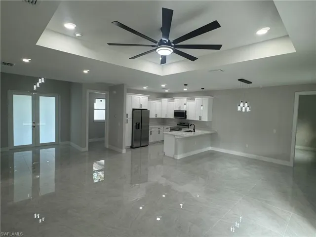 Kitchen featuring decorative light fixtures, light tile floors, appliances with stainless steel finishes, and a raised ceiling