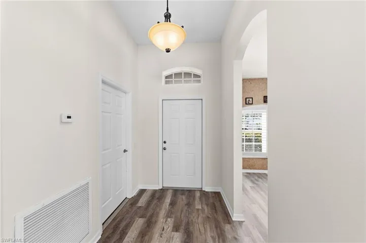 Entrance foyer featuring arched walkways, dark wood-style flooring, and a high ceiling